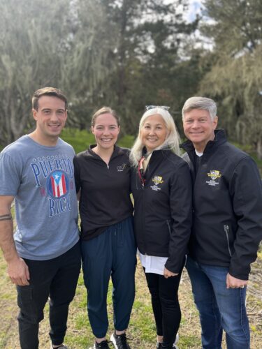Retired Navy Rear Admiral James Loeblein and his wife, retired Navy Captain Carol Loeblein and Delaney Rosario Cru Military staff standing and smiling 